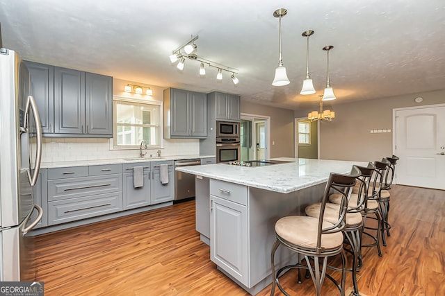 kitchen with a center island, sink, hanging light fixtures, decorative backsplash, and stainless steel appliances