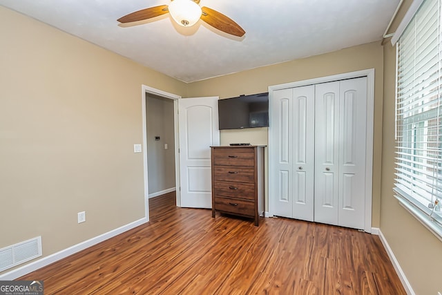 unfurnished bedroom featuring dark hardwood / wood-style flooring, ceiling fan, and a closet