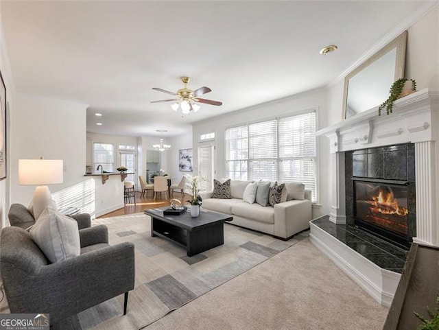 carpeted living room with ceiling fan, crown molding, and a tile fireplace