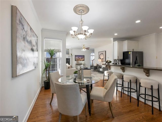 dining space with ceiling fan with notable chandelier, dark hardwood / wood-style flooring, crown molding, and a wealth of natural light