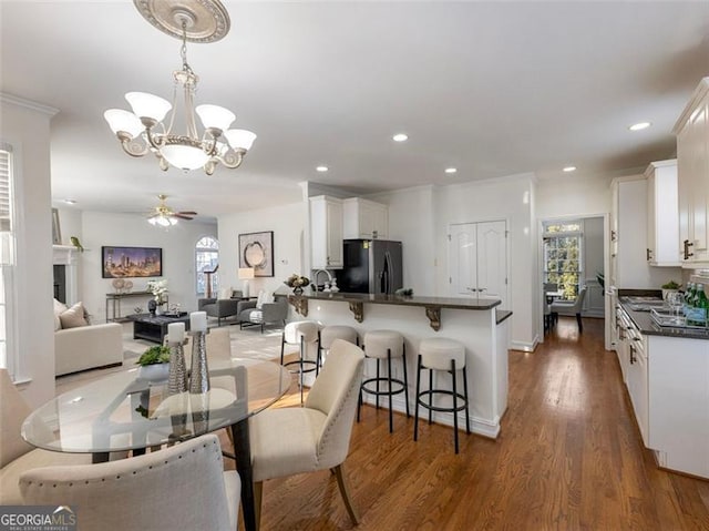 dining room featuring ceiling fan with notable chandelier and dark hardwood / wood-style flooring