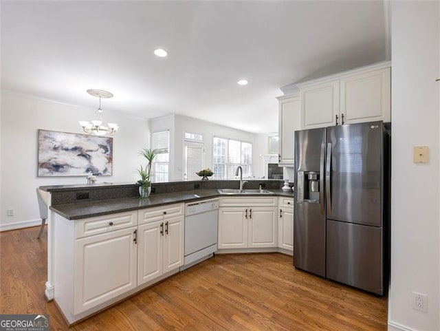 kitchen featuring white dishwasher, white cabinets, sink, a notable chandelier, and stainless steel fridge with ice dispenser