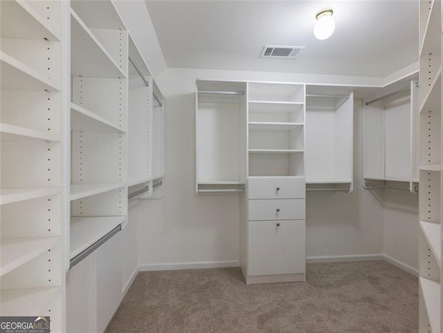 walk in closet featuring light colored carpet