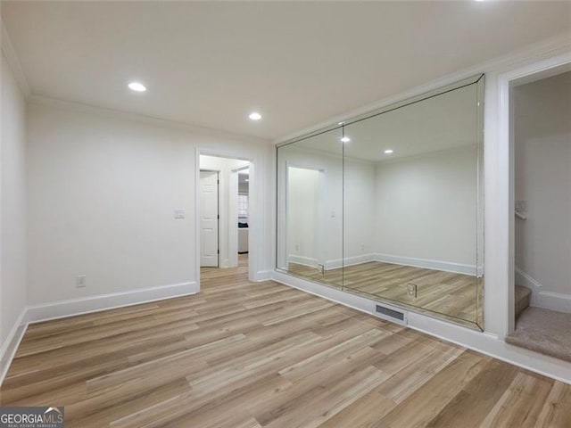 unfurnished bedroom with light hardwood / wood-style floors, crown molding, and a closet