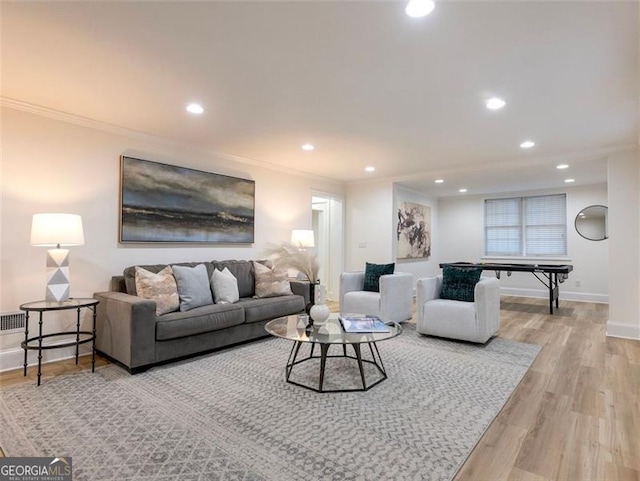 living room with ornamental molding and light hardwood / wood-style flooring