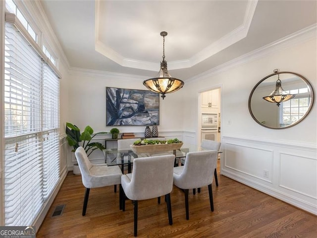 dining room featuring dark hardwood / wood-style floors, a raised ceiling, and ornamental molding