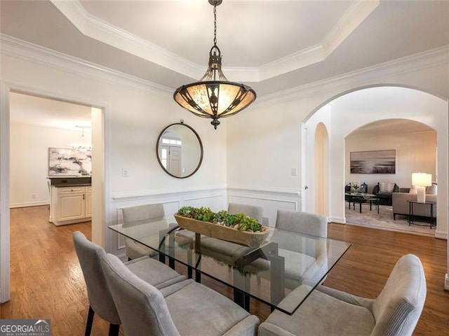 dining room with a tray ceiling, light hardwood / wood-style floors, and ornamental molding