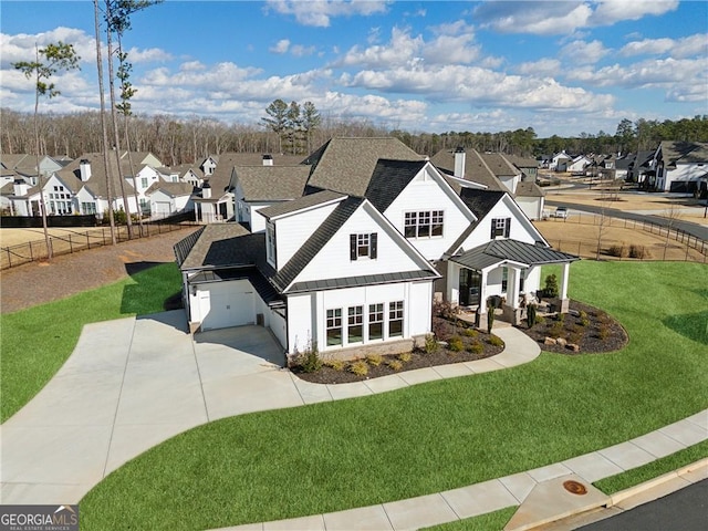 view of front of property with fence, driveway, a residential view, a front lawn, and a standing seam roof