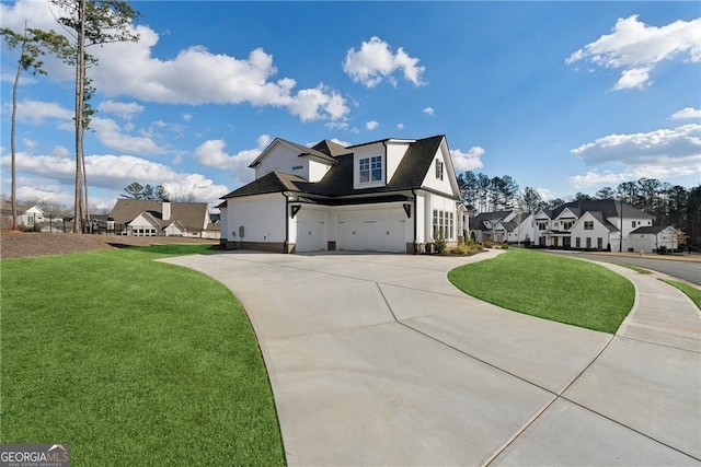 view of side of property featuring a garage, concrete driveway, a yard, and a residential view