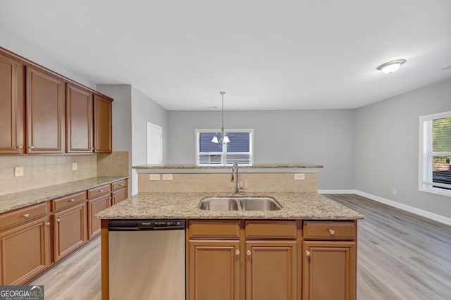 kitchen featuring light wood-type flooring, sink, pendant lighting, an inviting chandelier, and dishwasher