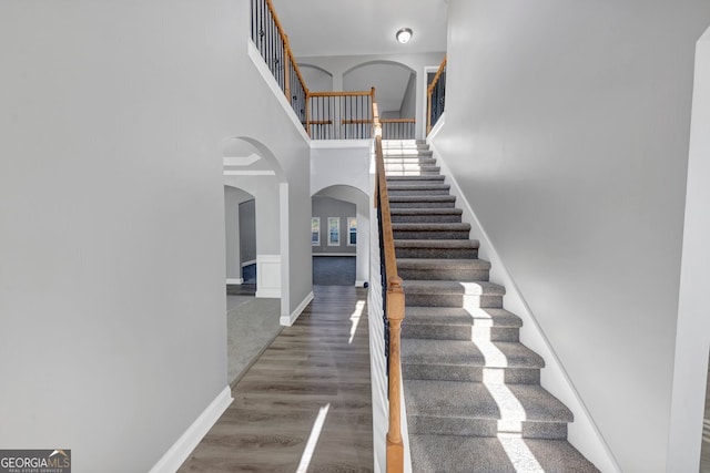 stairs featuring hardwood / wood-style floors and a towering ceiling