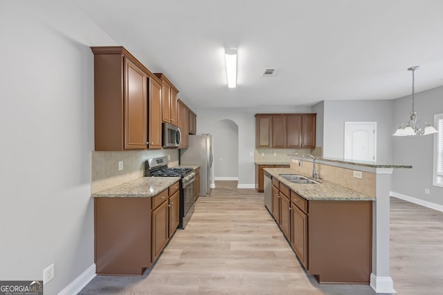 kitchen with appliances with stainless steel finishes, sink, decorative light fixtures, light hardwood / wood-style flooring, and a chandelier