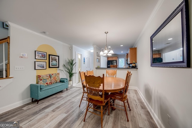 dining area featuring light hardwood / wood-style flooring, ornamental molding, and an inviting chandelier