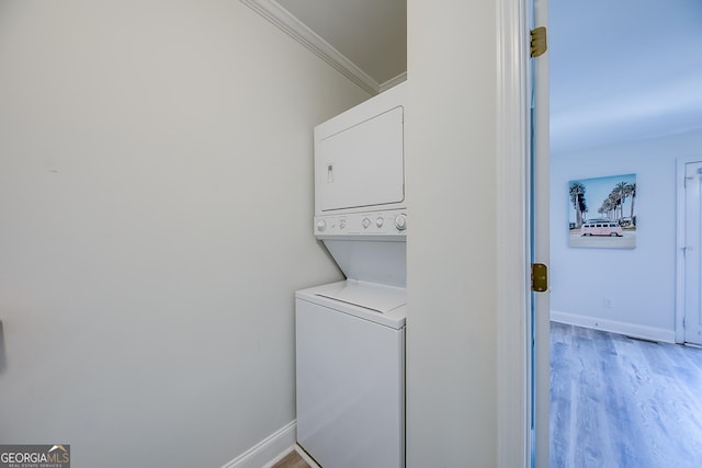 laundry room featuring wood-type flooring, stacked washer and clothes dryer, and ornamental molding