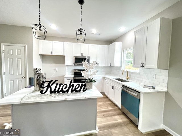 kitchen featuring hanging light fixtures, white cabinetry, sink, and stainless steel appliances