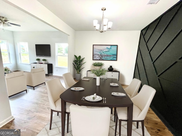 dining area with ceiling fan with notable chandelier and light hardwood / wood-style flooring