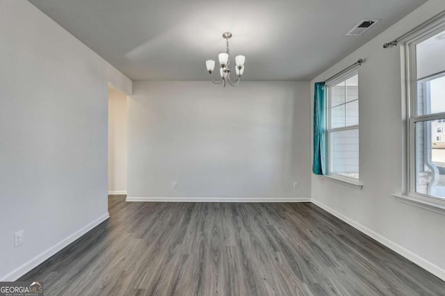 unfurnished room featuring dark hardwood / wood-style floors and an inviting chandelier