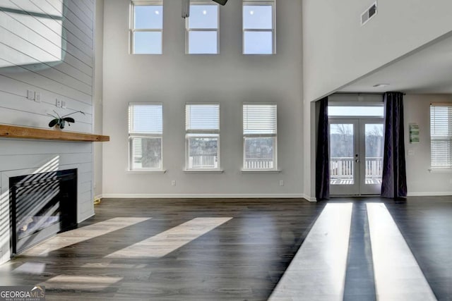 unfurnished living room featuring a fireplace, a wealth of natural light, french doors, and dark hardwood / wood-style flooring