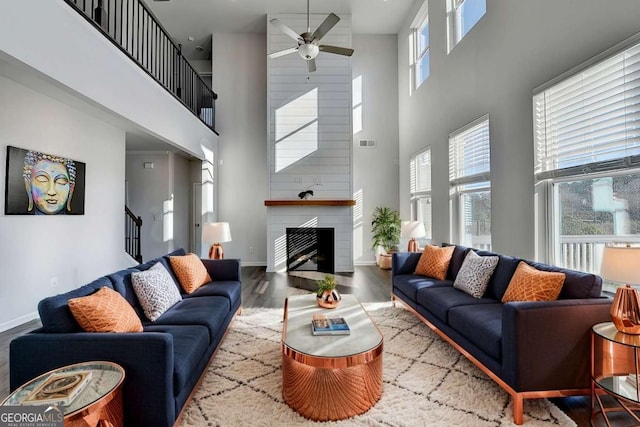 living room with a fireplace, a high ceiling, plenty of natural light, and wood-type flooring