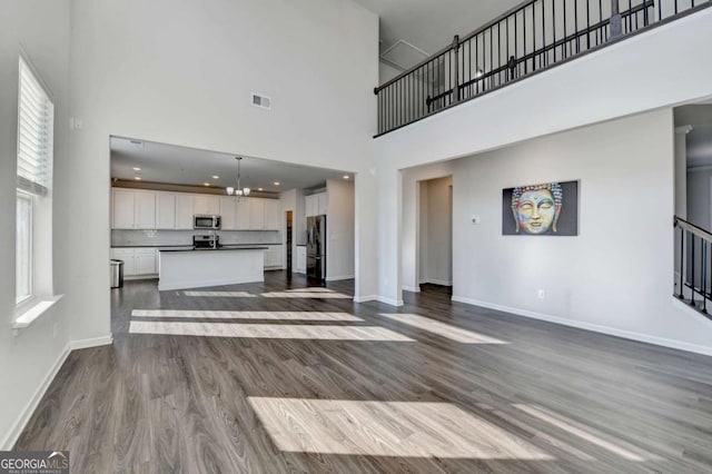 unfurnished living room featuring hardwood / wood-style flooring, a high ceiling, and a chandelier