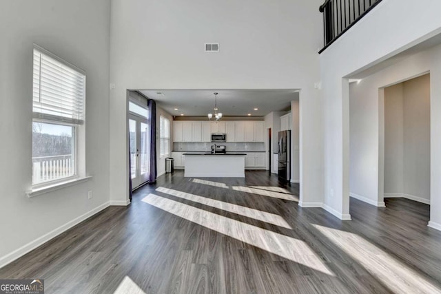 living room with a towering ceiling, dark wood-type flooring, and an inviting chandelier