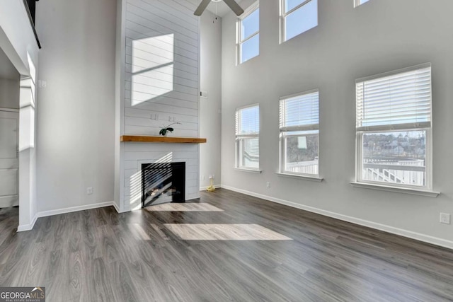 unfurnished living room with dark hardwood / wood-style flooring, a wealth of natural light, and a large fireplace