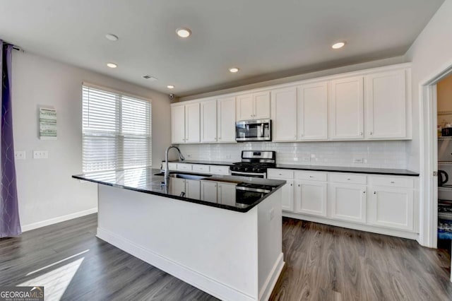 kitchen with dark hardwood / wood-style flooring, stainless steel appliances, sink, a center island with sink, and white cabinets