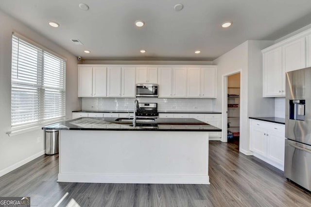 kitchen with sink, stainless steel appliances, an island with sink, white cabinets, and hardwood / wood-style flooring