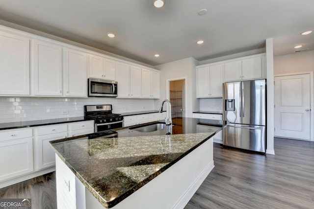 kitchen featuring sink, stainless steel appliances, an island with sink, decorative backsplash, and white cabinets