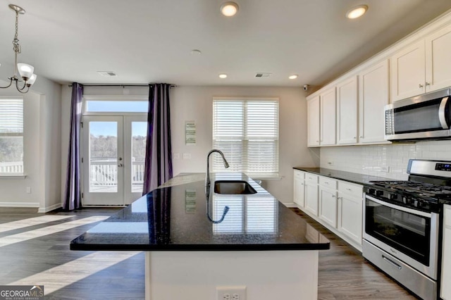 kitchen featuring white cabinets, appliances with stainless steel finishes, a center island with sink, and sink