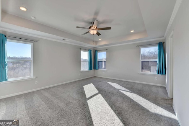 spare room featuring dark colored carpet, ceiling fan, a raised ceiling, and crown molding