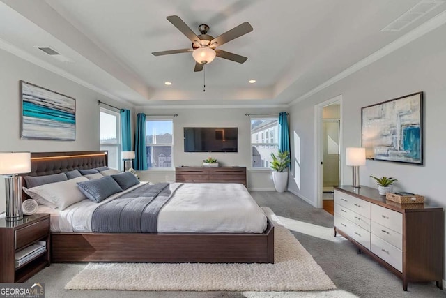 carpeted bedroom with connected bathroom, a tray ceiling, ceiling fan, and ornamental molding