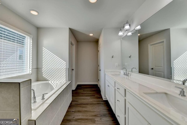 bathroom featuring hardwood / wood-style flooring, vanity, and a relaxing tiled tub