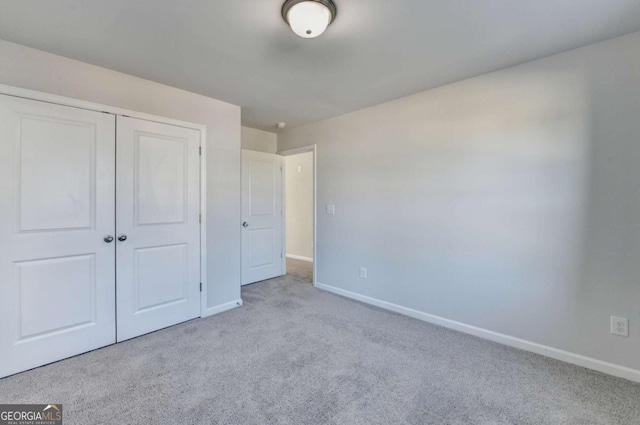 unfurnished bedroom with light colored carpet and a closet