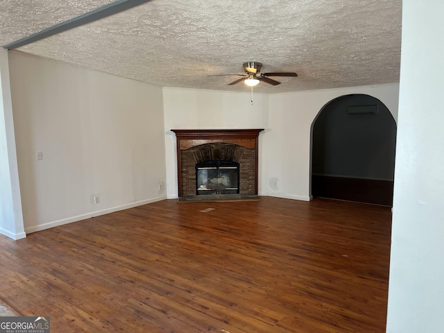 unfurnished living room with a fireplace, a textured ceiling, dark hardwood / wood-style floors, and ceiling fan