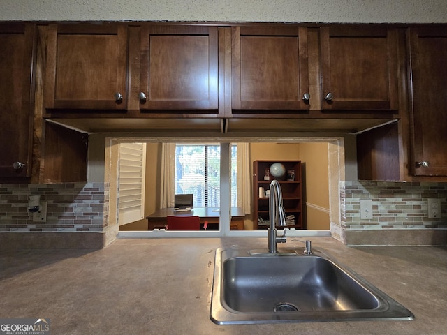 kitchen featuring sink, dark brown cabinetry, and tasteful backsplash