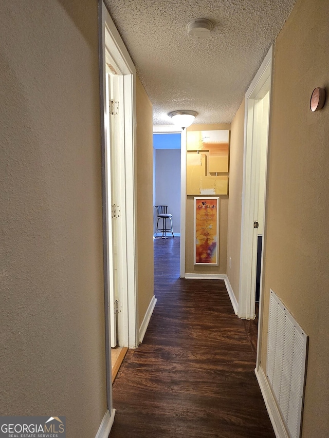 hallway with dark hardwood / wood-style flooring and a textured ceiling