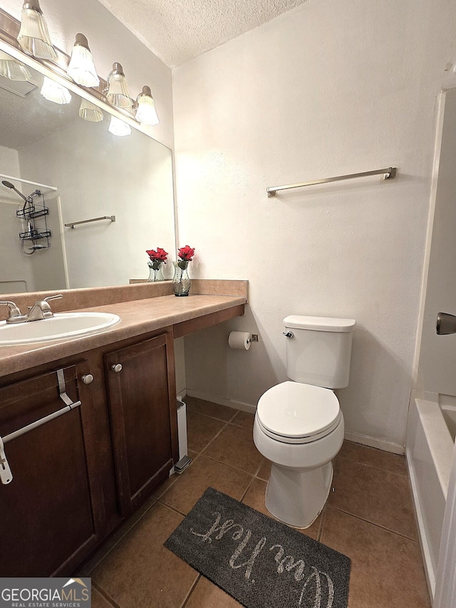 bathroom with toilet, vanity, tile patterned floors, and a textured ceiling