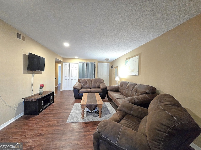 living room with a textured ceiling and dark hardwood / wood-style flooring