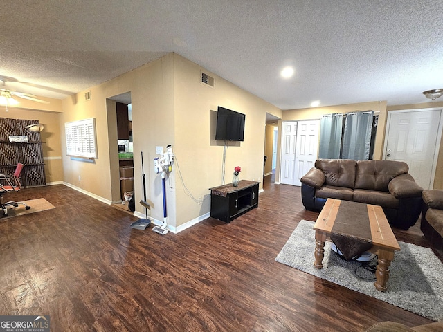 living room with ceiling fan, dark hardwood / wood-style flooring, and a textured ceiling