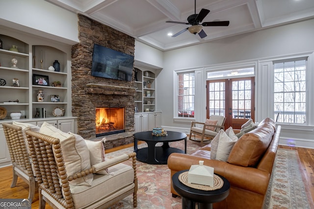 living room with french doors, coffered ceiling, light hardwood / wood-style flooring, beamed ceiling, and a fireplace