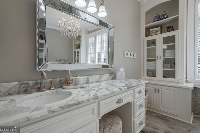 bathroom featuring built in features, vanity, a notable chandelier, and ornamental molding