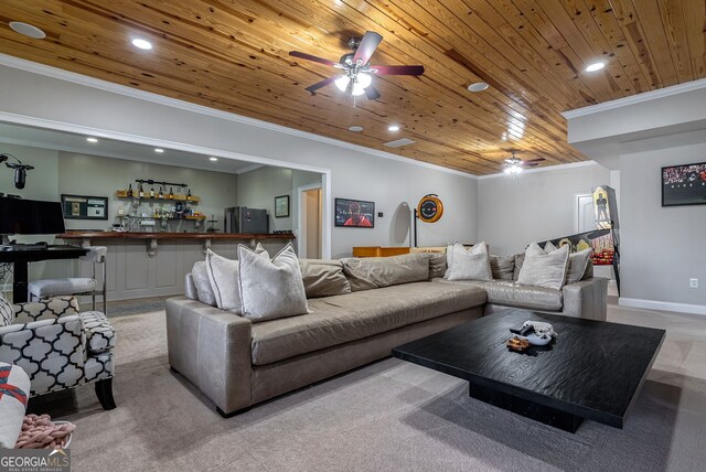 carpeted living room featuring crown molding, bar, wooden ceiling, and ceiling fan