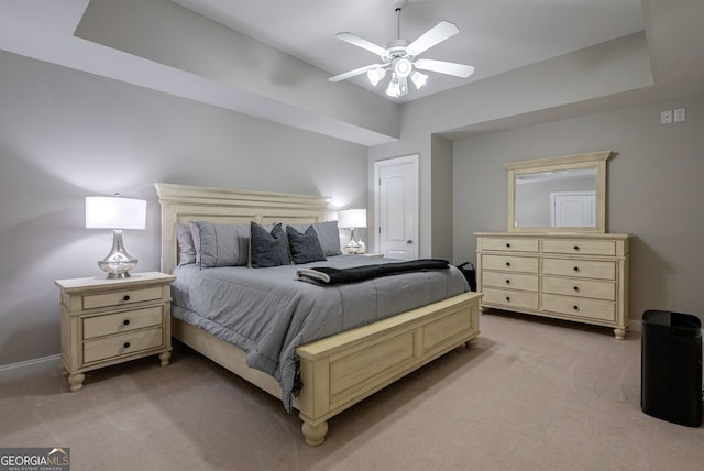 carpeted bedroom featuring a raised ceiling and ceiling fan