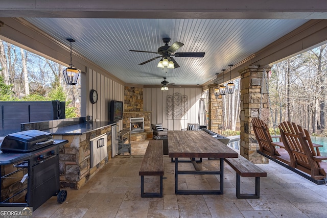 view of patio featuring an outdoor stone fireplace, ceiling fan, an outdoor kitchen, and a grill