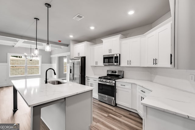 kitchen with sink, white cabinetry, decorative light fixtures, an island with sink, and stainless steel appliances