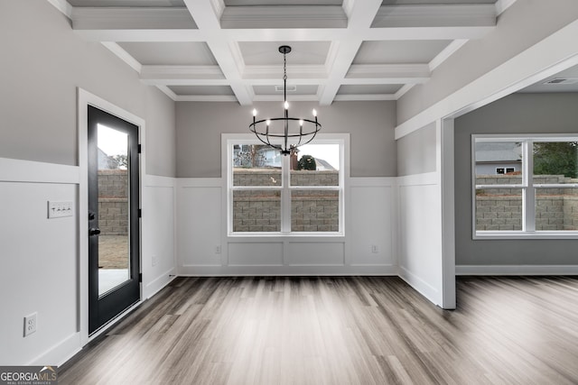 unfurnished dining area featuring an inviting chandelier, wood-type flooring, coffered ceiling, and beamed ceiling