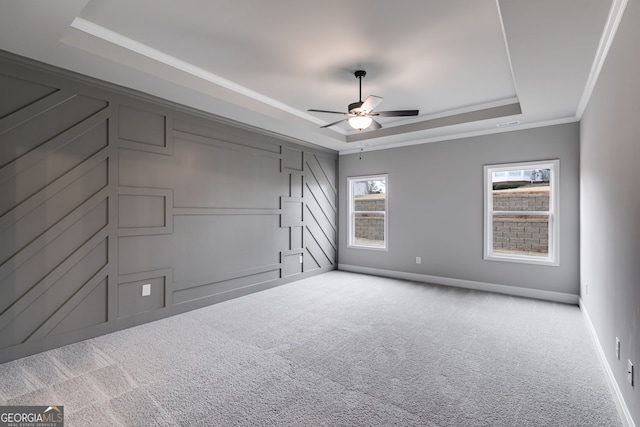 carpeted empty room featuring ornamental molding, ceiling fan, and a tray ceiling