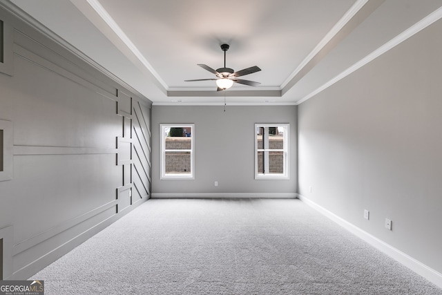 carpeted empty room featuring ornamental molding, a healthy amount of sunlight, ceiling fan, and a tray ceiling