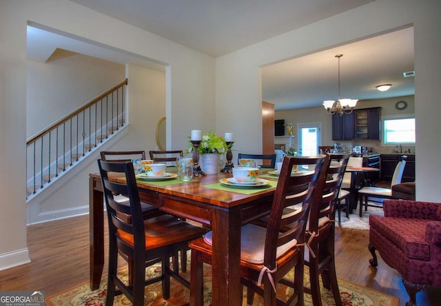 dining space featuring sink, dark wood-type flooring, and an inviting chandelier